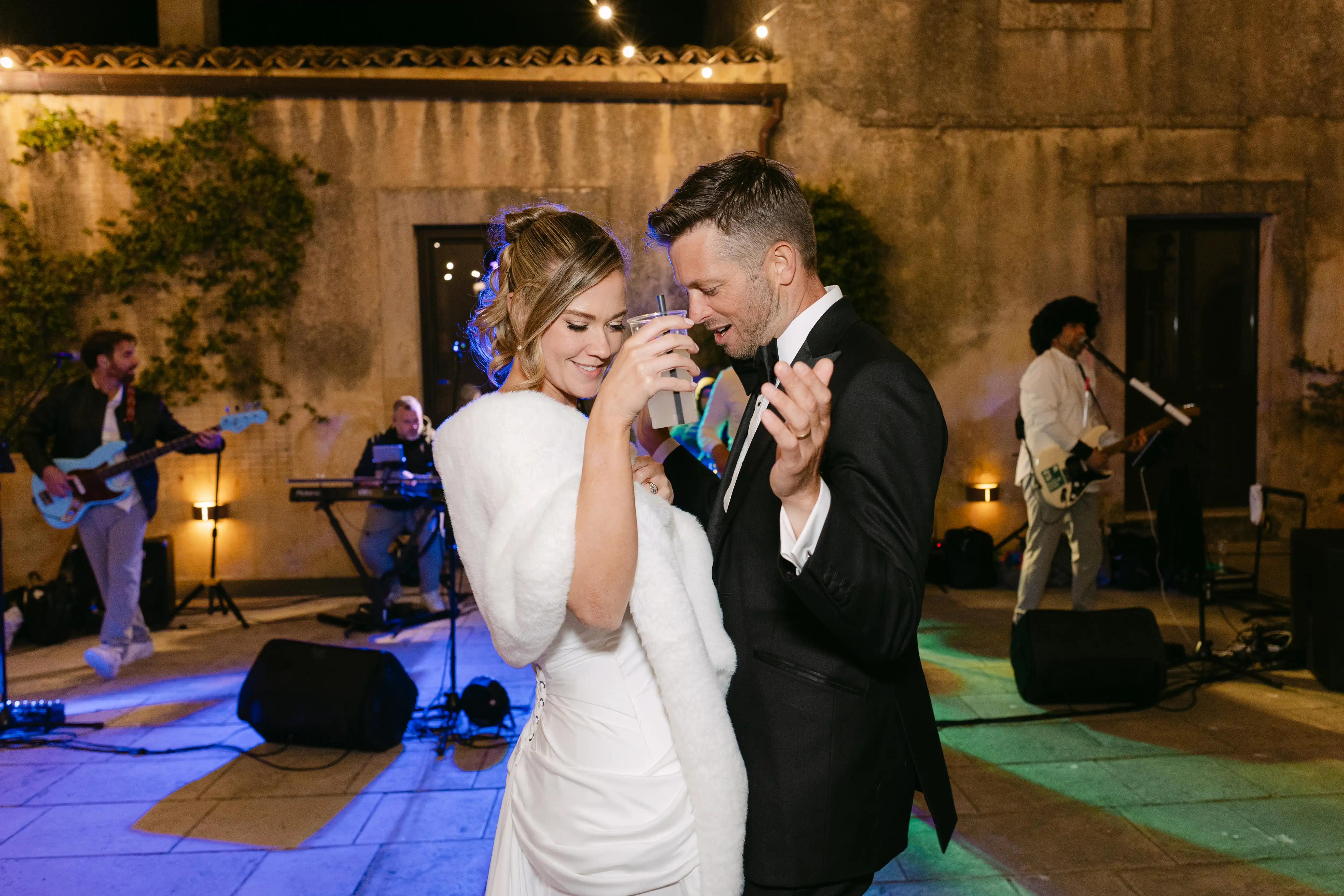 Bride and groom dancing together during the wedding party with a live band performing in the background.